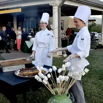 Two culinary students standing near a serving table