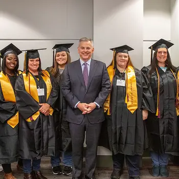 Student inmates pose for graduation photo with state governor and college president.