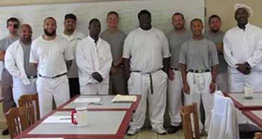 Twelve chef inmates lined up with the teaching assistant wearing a white hat.