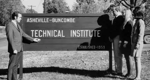 Man with three students beside A-B Tech sign in 1960s