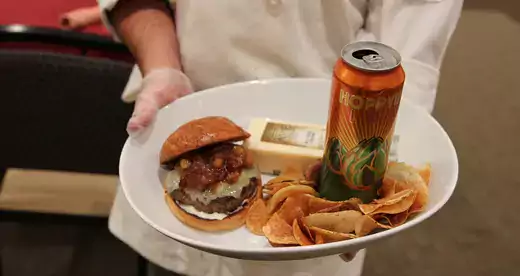 Chef holding white plate with hamburger and chips