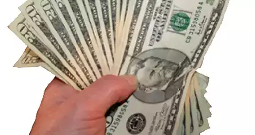 A hand holding several 20 dollar bills