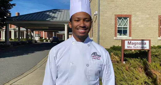 Young man in chef's uniform standing outside a building