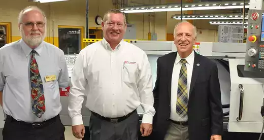 Three men in front of a CNC machine