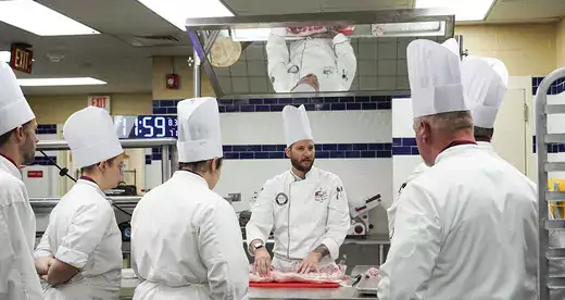Chef standing behind table with 5 students watching