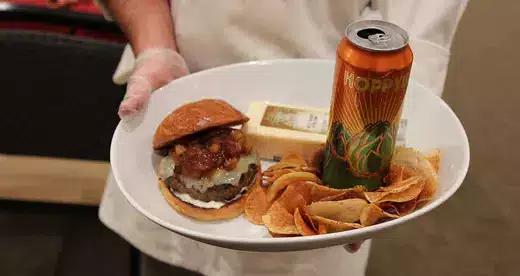 Chef holding white plate with hamburger and chips