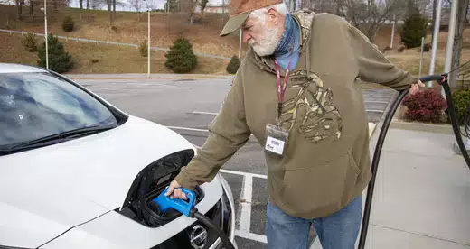 Man putting charger on electric car