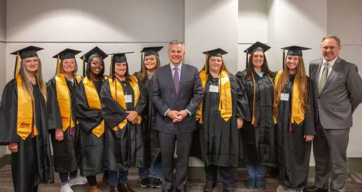 Student inmates pose for graduation photo with state governor and college president.