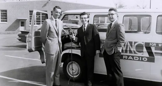 Three men in front of a radio broadcasting van