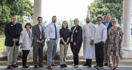 10 men and women standing outside under a portico