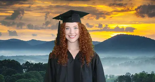 Woman in cap and gown in front of mountains