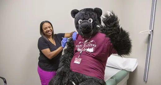 Trailblazer Bear receiving a vaccine from the health clinic