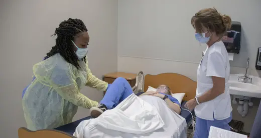Two women standing by an occupied hospital bed
