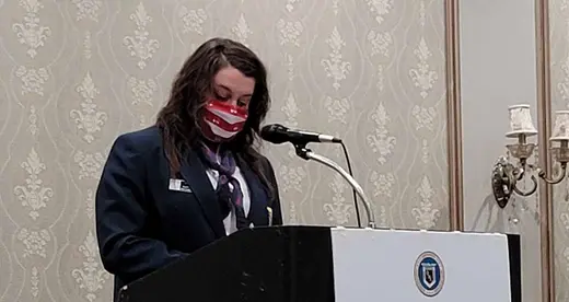 Woman in a face mask standing behind a lectern