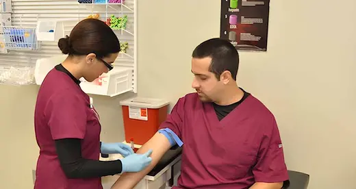 Woman drawing blood from the arm of a man