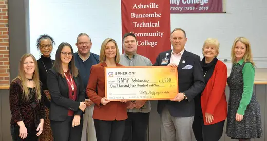 A group of smiling people with an oversized check