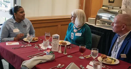 Student eating lunch with two donors