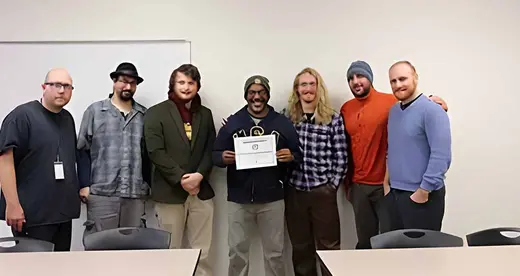 Heath Moody and his students in the Issues In Sustainability class against a wall with a certificate.