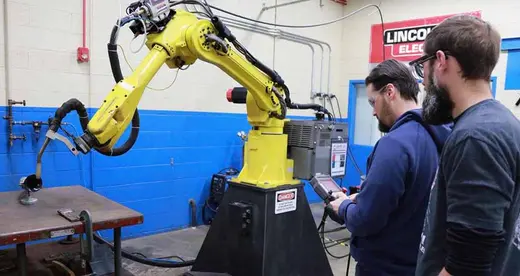 Two men working with a robit