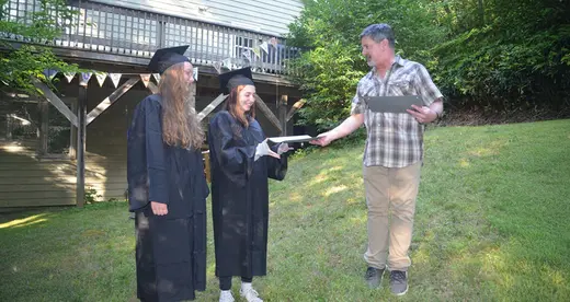 High School Handoff: Claire Bowling, left, and Amelia Darnell receive their high school diplomas in July 2019 from Chuck Bowling, who served as principal of their home school, Parkview Academy. Photo by Roger Darnell