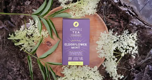 Box of tea sitting beside white flowers