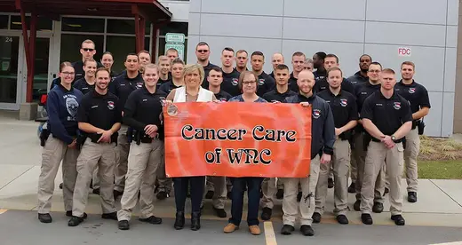 28 students and two women holding a banner reading Cancer Care of WNC