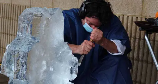 Man using chisel on a block of ice