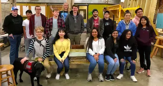 A group of construction students with a newly constructed bee bench