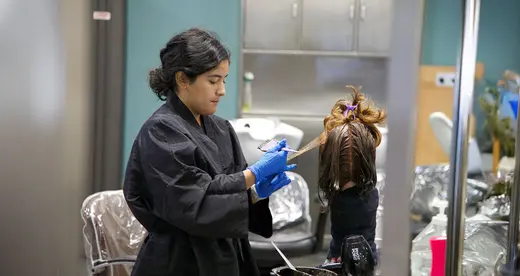 A woman working on a head of hair