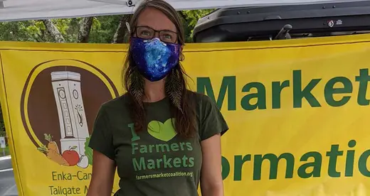 Woman wearing a mask in farmers market booth