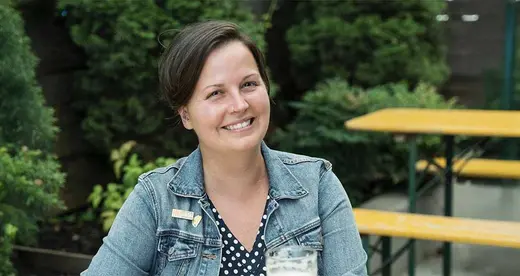 Woman sitting at a picnic table with a beer