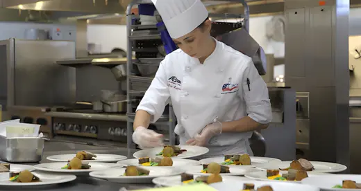 Student chef preparing plates of food.