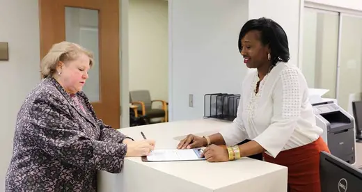 Office Assistant at a desk with a patient
