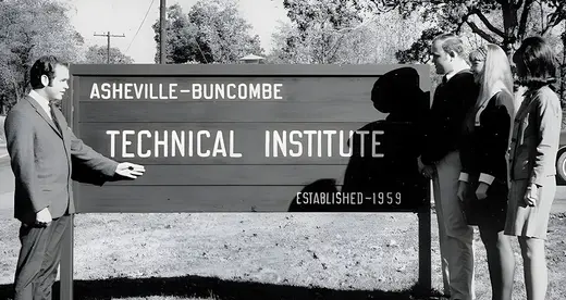 Man with three students beside A-B Tech sign in 1960s