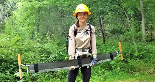 Young woman holding tree saw in a forest