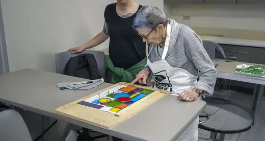 Older woman with stained glass project on table