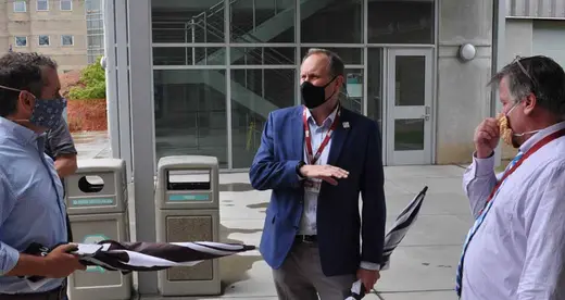 Three men wearing masks and talking