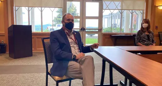 Man sitting at table wearing mask and orange checkerboard socks