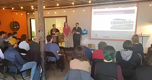 Students Nora Steppe, Jennifer Webb and Farra Lomasney standing in front of an audience.