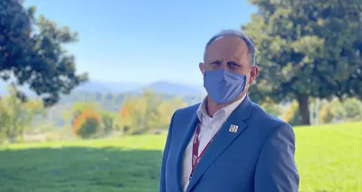 Dr. John Gossett standing outside wearing a blue face mask