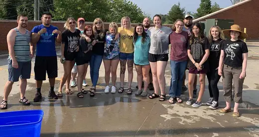 A group of wet students standing on a concrete surface. 