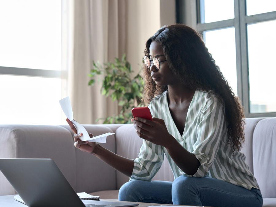 Young black woman holding paper paying bills