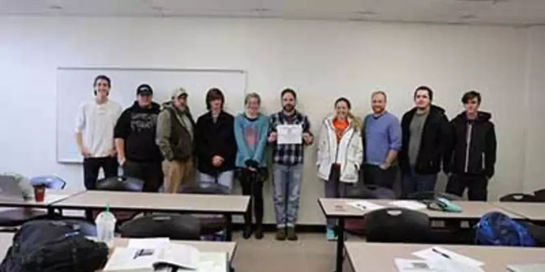 Heath Moody and his students in the Introduction to Sustainability class against a wall with a certificate.