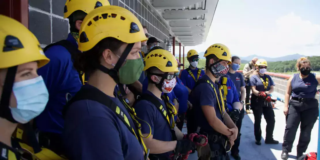Students in rappelling harnesses and helmets