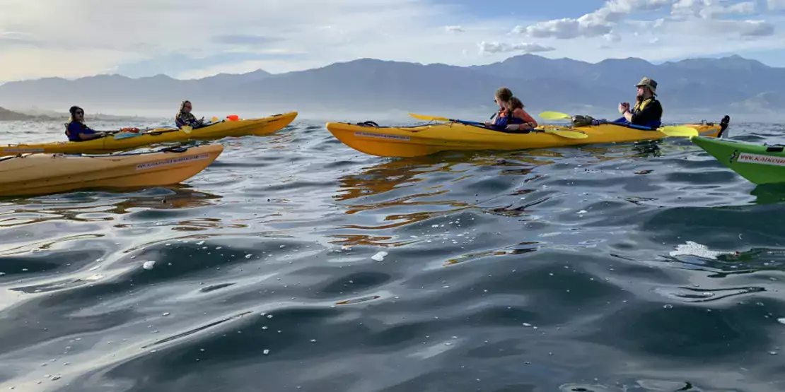 People kayaking with mountains in the background