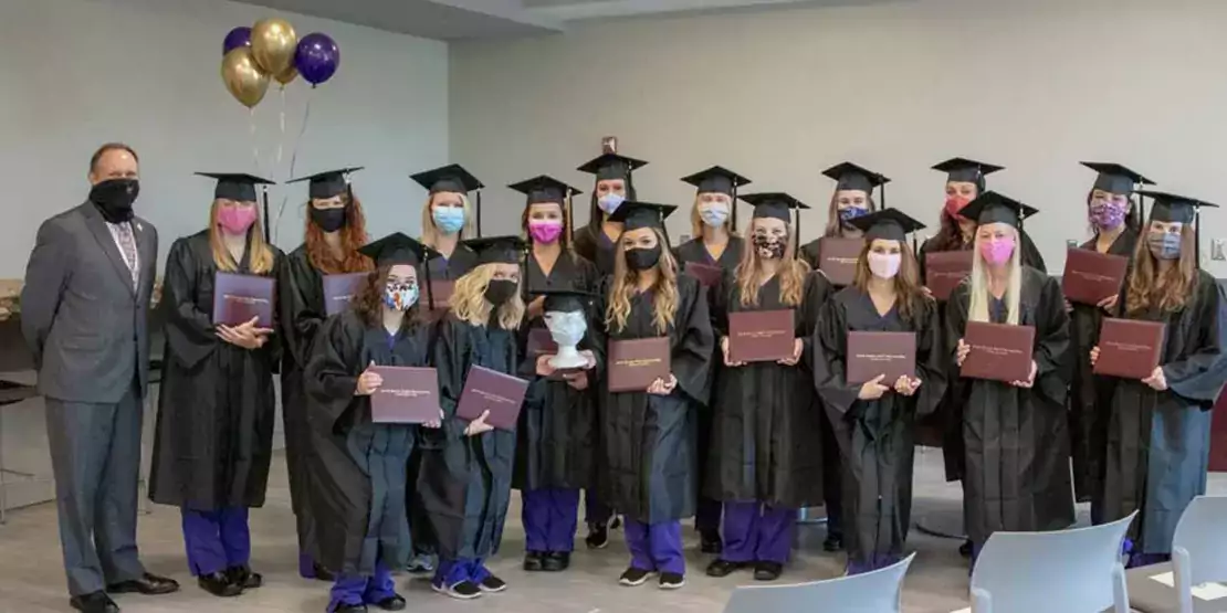 Group of students in caps and gowns wearing facemasks