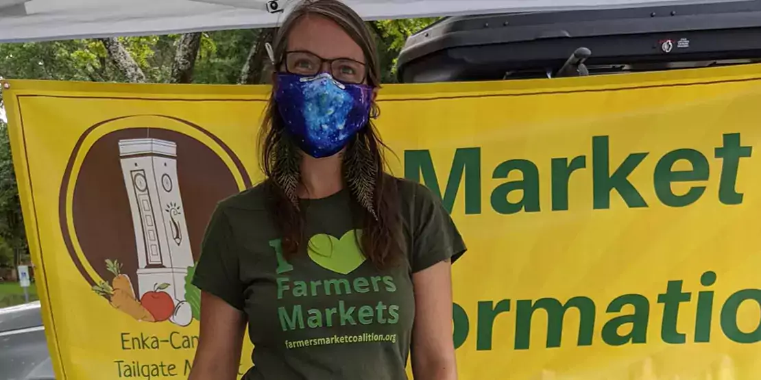 Woman wearing a mask in farmers market booth 
