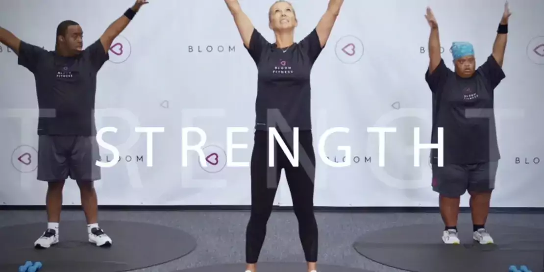 Three people on yoga mats standing upright with arms stretched