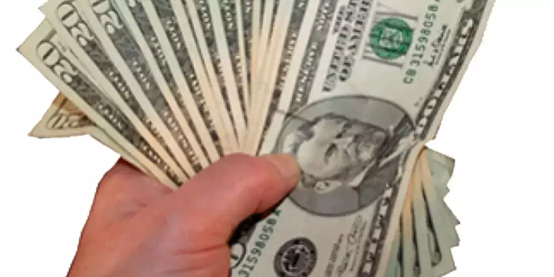 A hand holding several 20 dollar bills