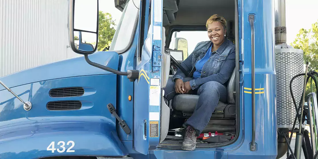 Woman sitting sideways in a truck with the door open.